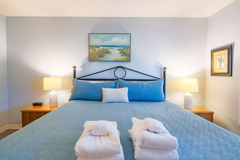 The master suite, which is located on the upper level, features a king bed and night stands with reading lamps.