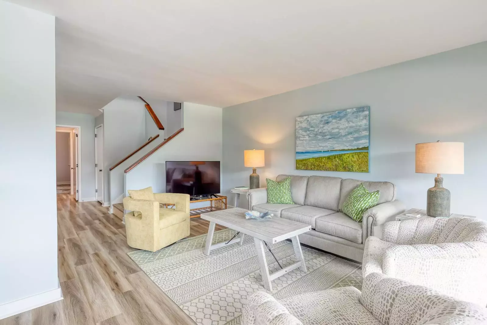 The living room features a large screen TV and beautiful art.