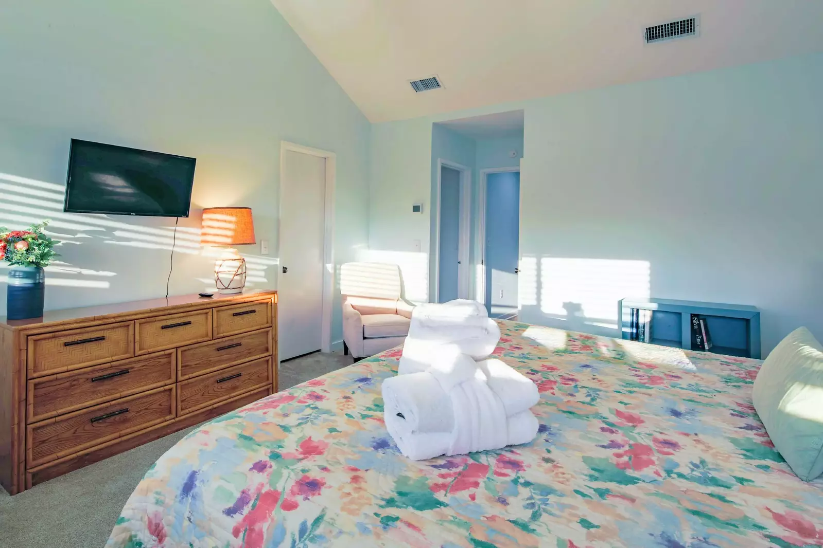 The master suite also features a dresser and wall-mounted TV.