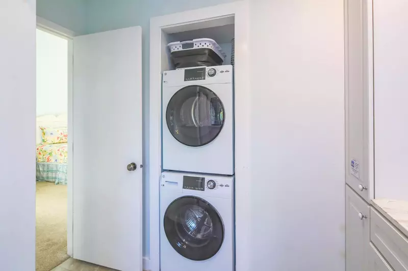 The stacked washing machine and dryer are located within the master bathroom.