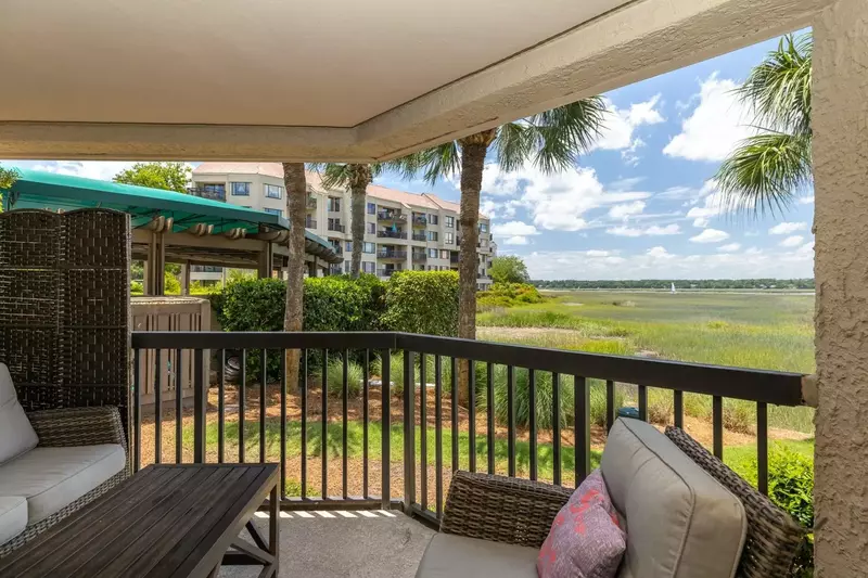 The private covered balcony features a seating area and beautiful marsh views.