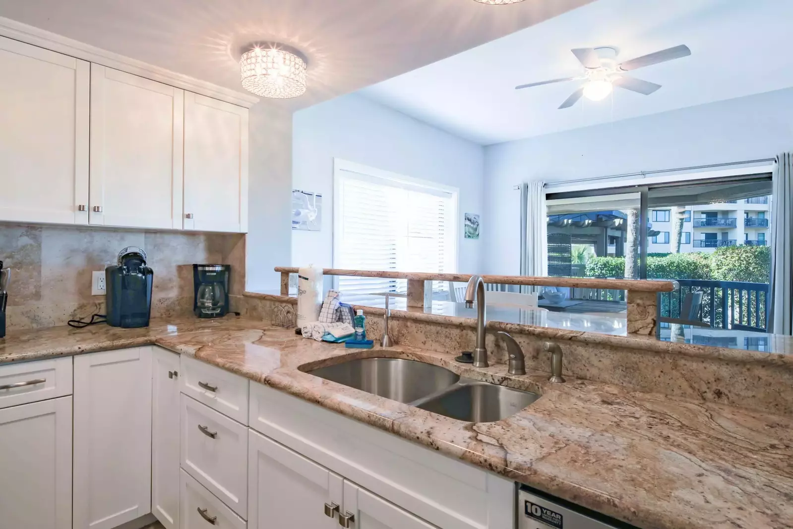 The kitchen features white cabinets, a dishwasher and coffee makers.