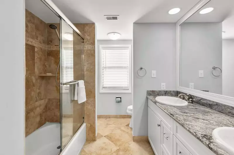 This bathroom with double sink vanity and a shower/tub combo is accessible from the hall and the guest bedroom.