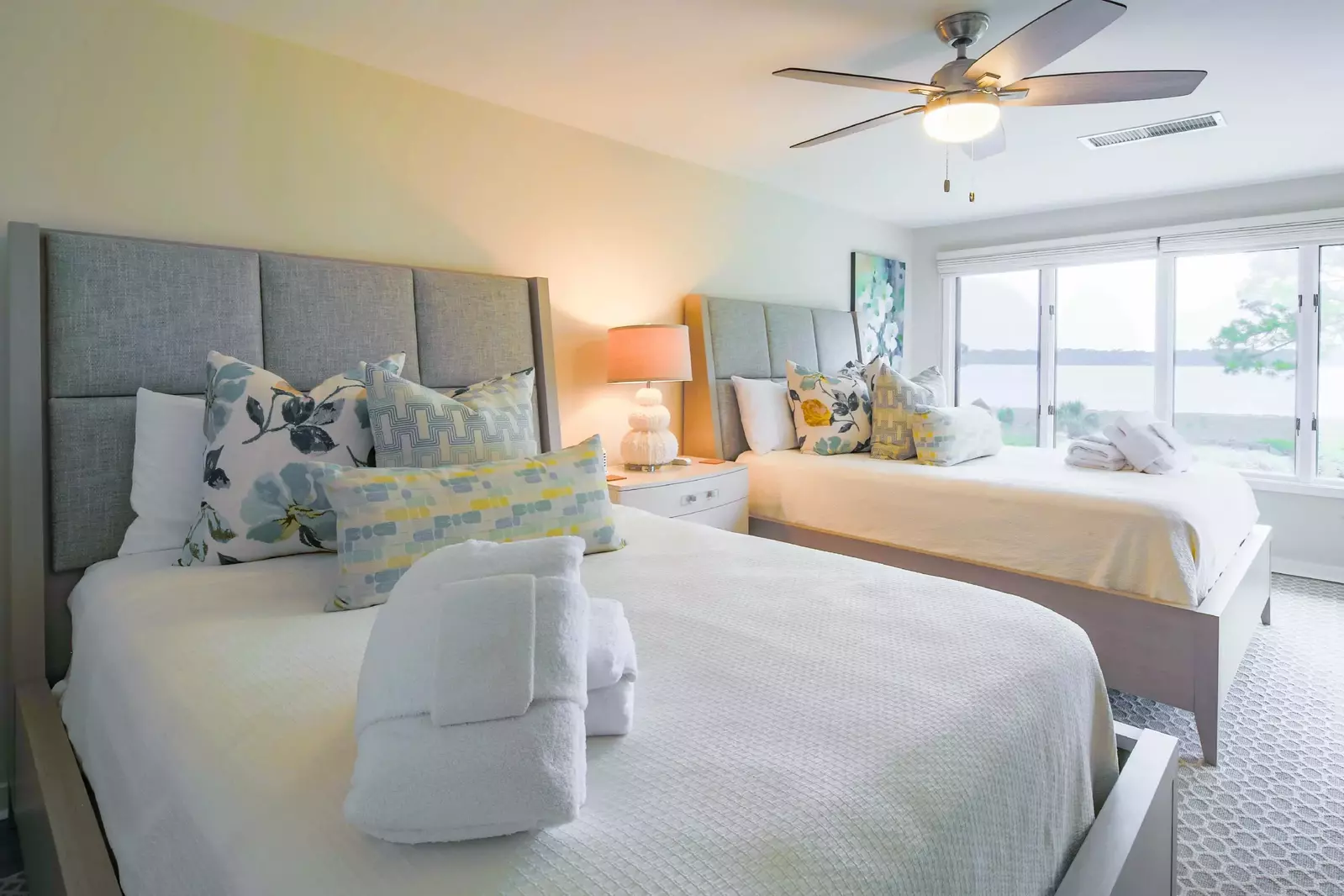 The guest suite features two queen beds, water views and a night stand with a reading lamp.