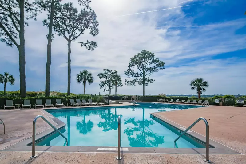 The community pool has a sun deck with lots of lounge chair seating.