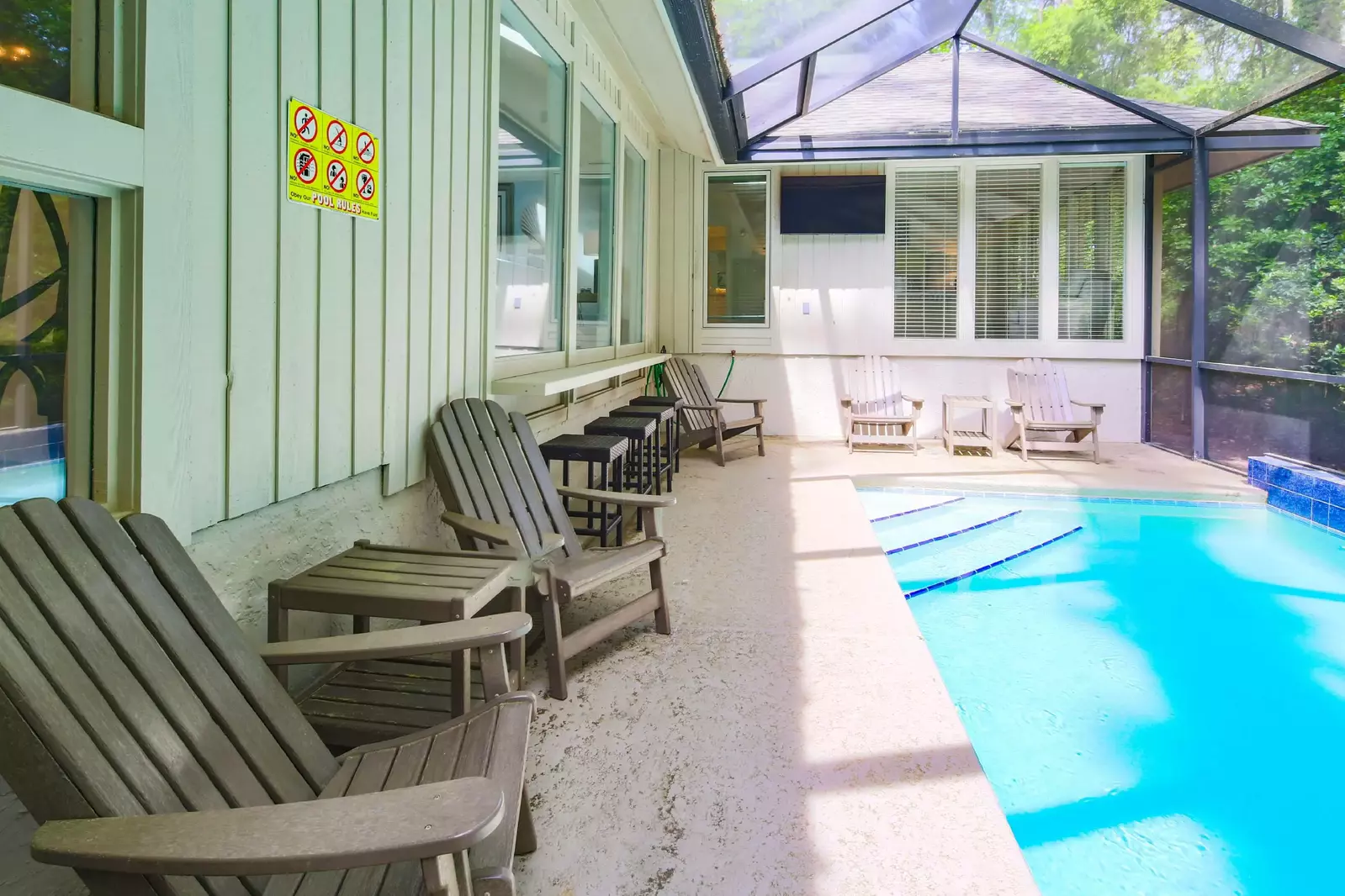 There are multiple chairs and stools alongside the pool.