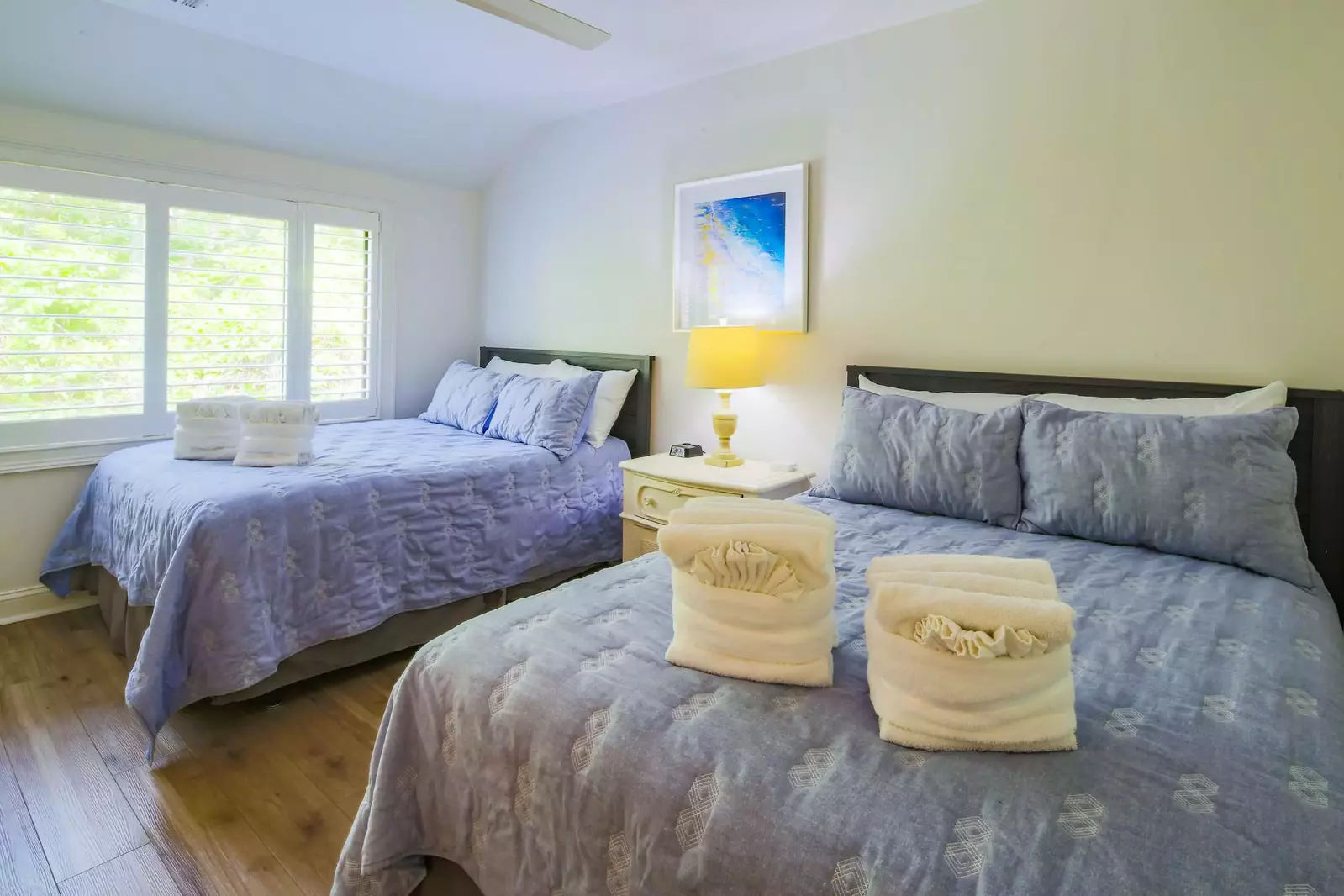 The guest bedroom features two full beds and a night stand with reading lamp.