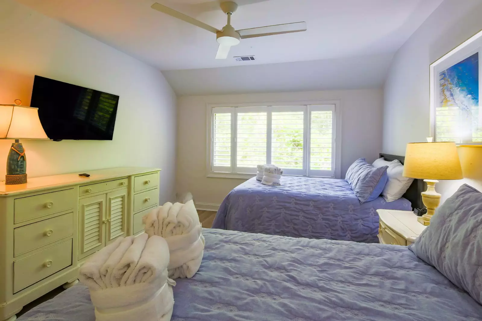 The guest bedroom also has a dresser, wall-mounted TV and ceiling fan.