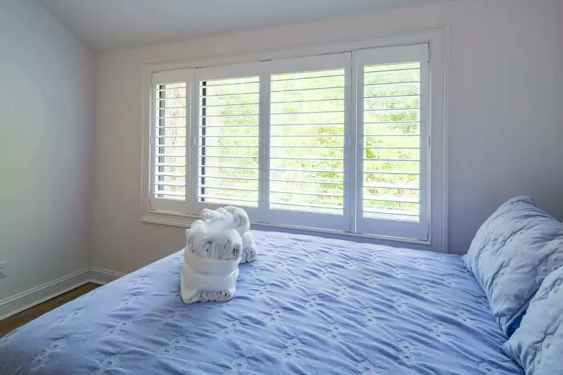 The guest bedroom has a large window that looks out the side of the home.