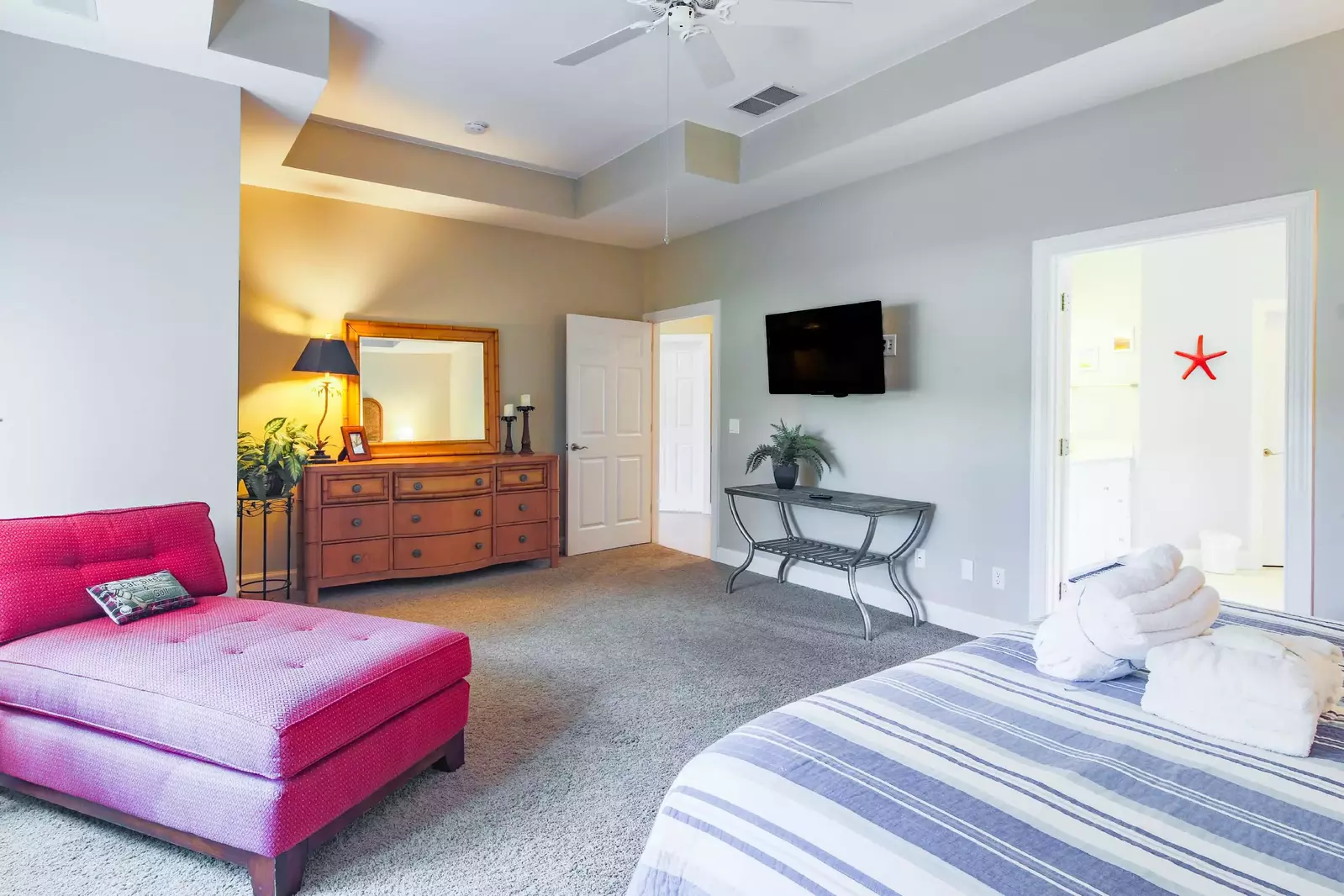 The master suite also features a dresser and wall-mounted flat screen TV.