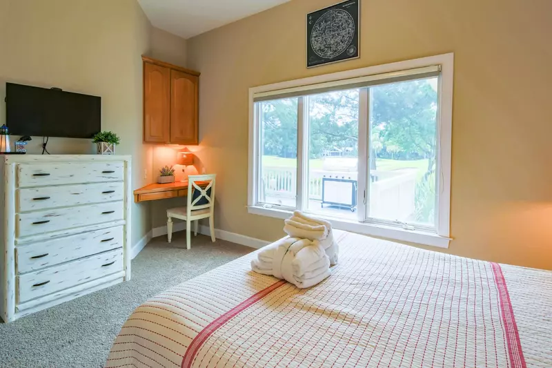 The queen bedroom also features a dresser, flat screen TV, small desk and views of the back porch.