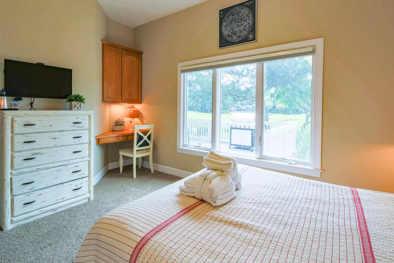 The queen bedroom also features a dresser, flat screen TV, small desk and views of the back porch.