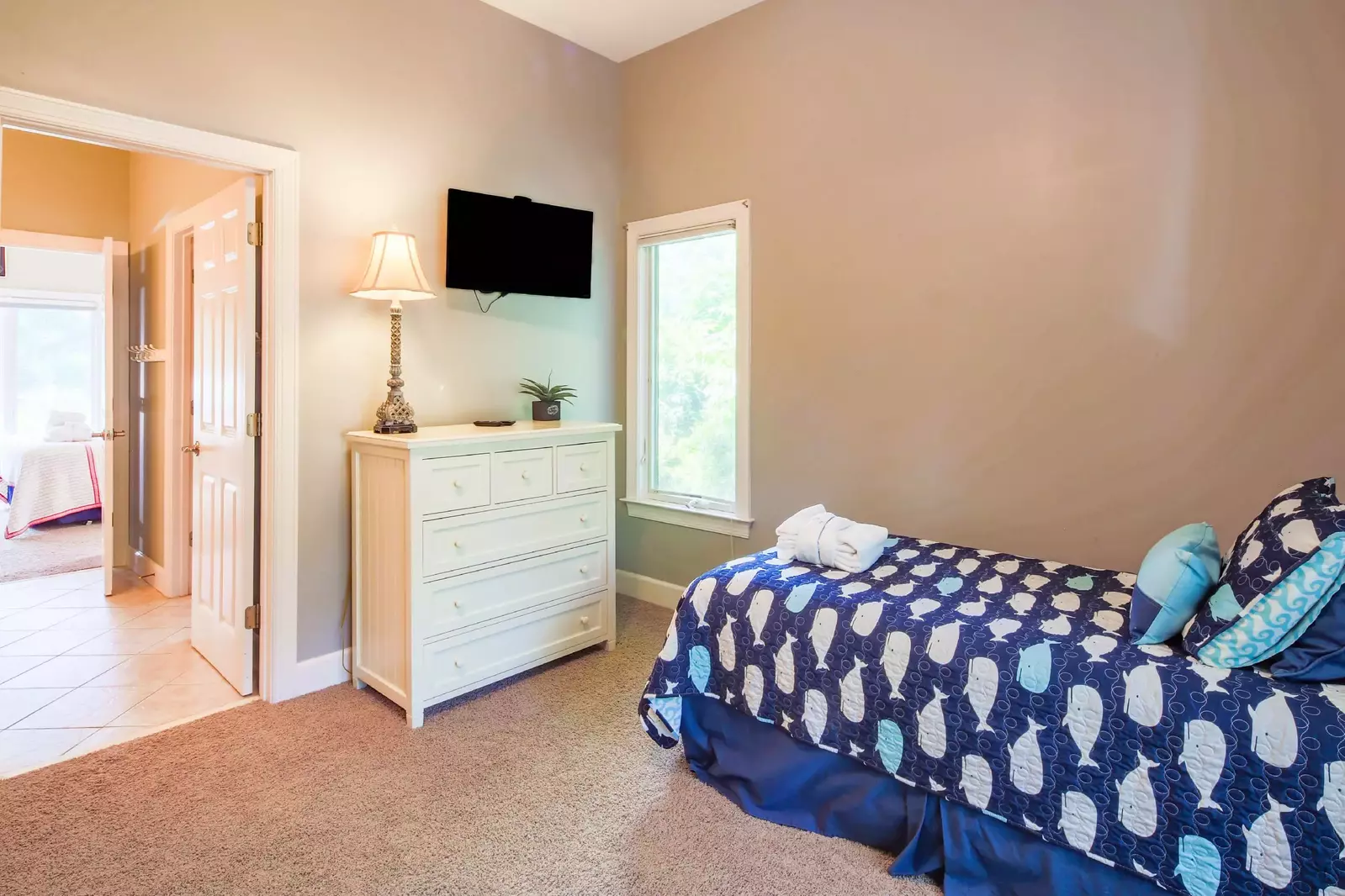 The twin bedroom also has a dresser, a wall-mounted TV and access to the jack & jill bathroom.