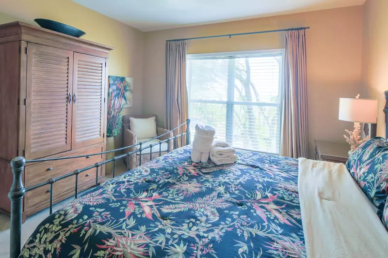 The master suite also features an armoire with flat screen TV, an arm chair and a ceiling fan.