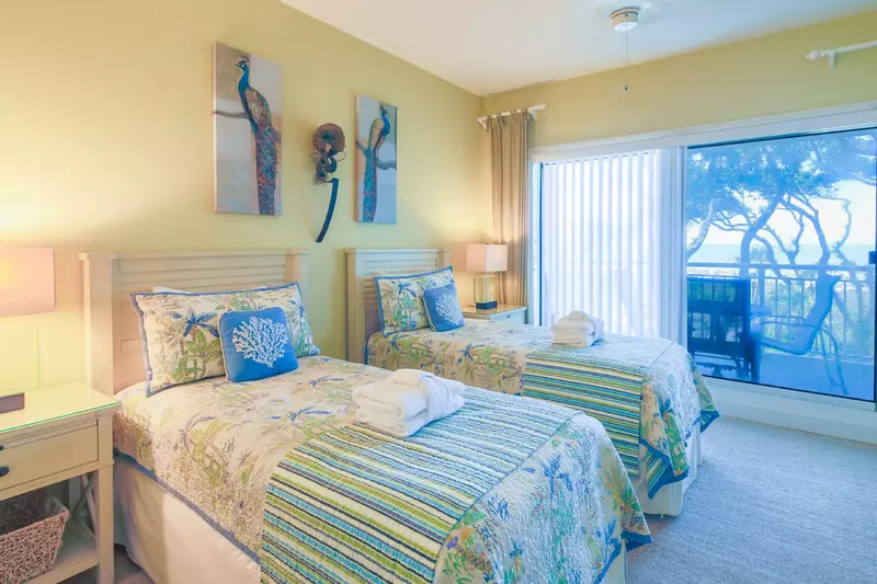 The guest suite features two twin beds, ocean views and sliding door access to the balcony.