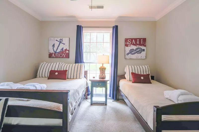 This guest bedroom has a full bed, a twin bed and a night stand with a reading lamp.