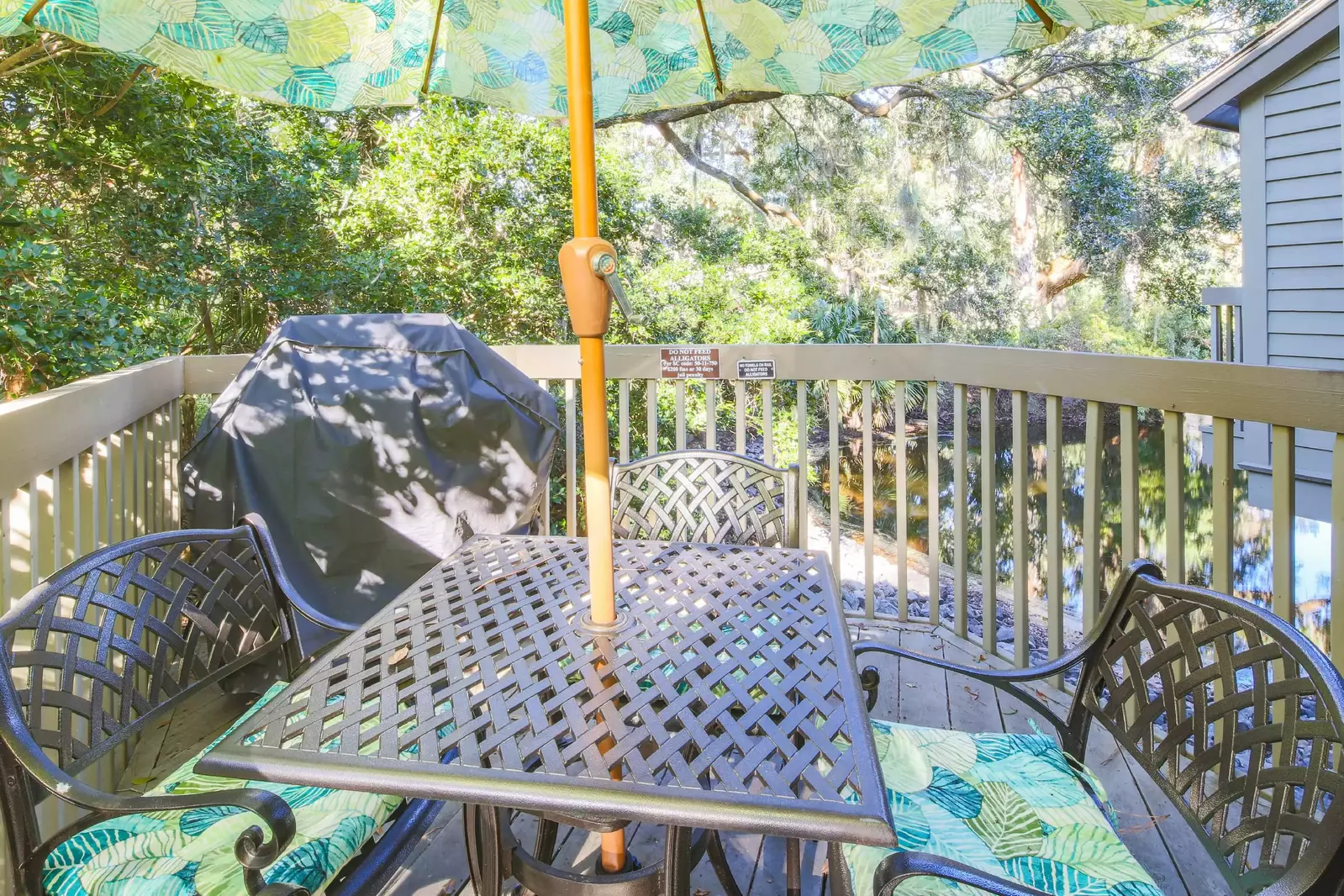 The deck features lagoon views, a gas grill and wrought iron table with an umbrella.