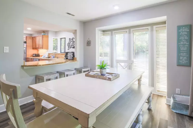 The kitchen opens into the dining area with 3 stools at the counter.