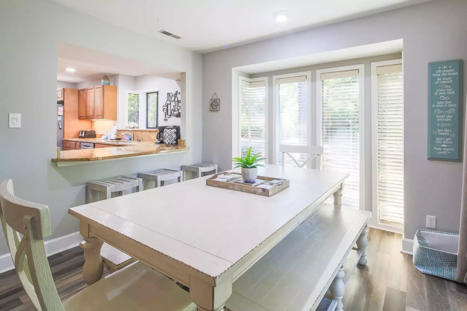 The kitchen opens into the dining area with 3 stools at the counter.