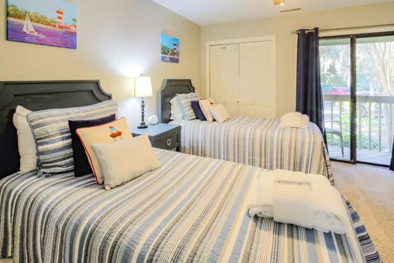 This twin bedroom features two twin beds, a night stand with reading lamp and a ceiling fan.
