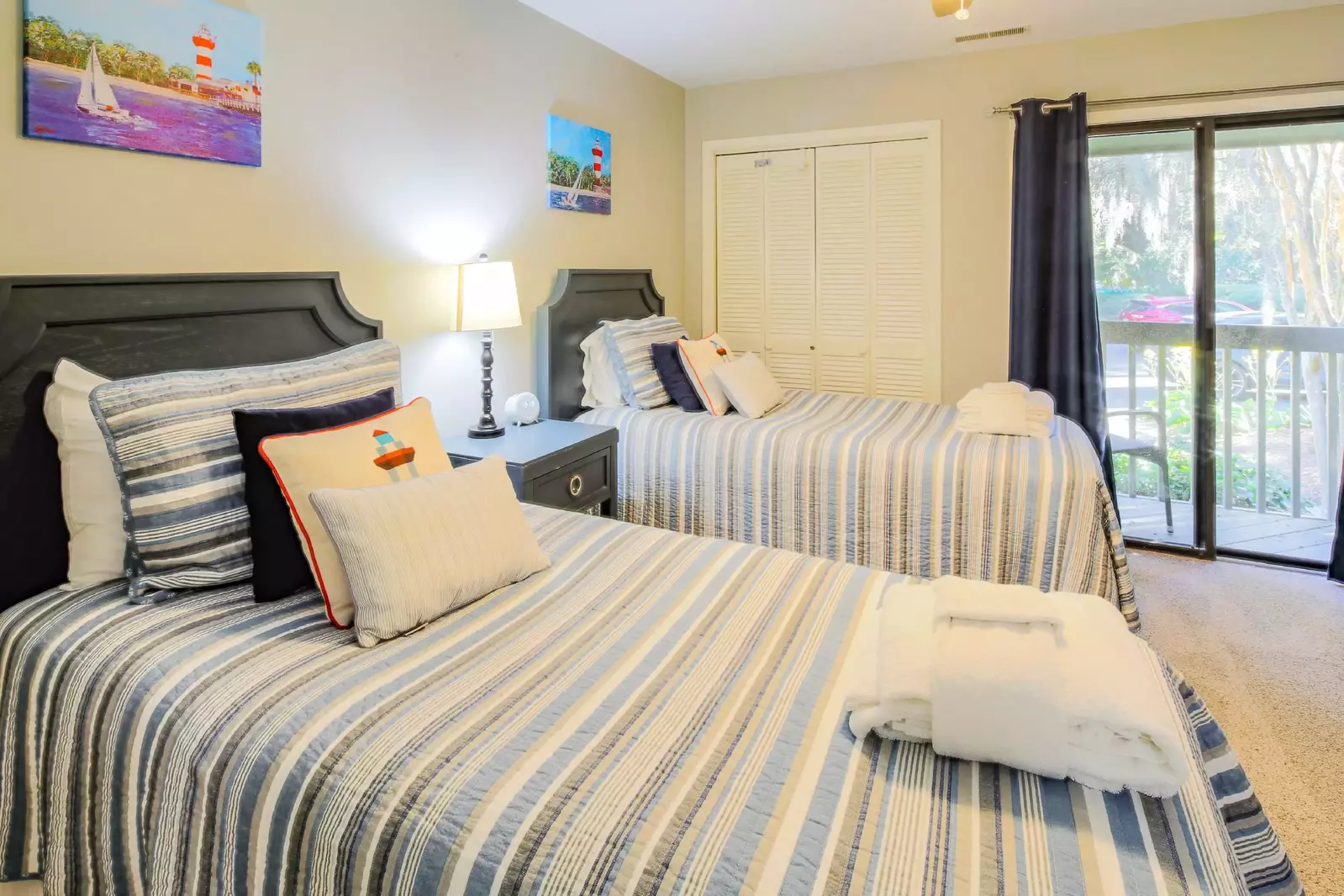 This twin bedroom features two twin beds, a night stand with reading lamp and a ceiling fan.
