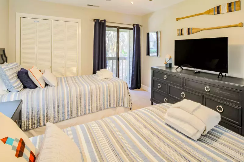 This twin bedroom also has sliding door access to a private deck and a dresser with a smart TV.
