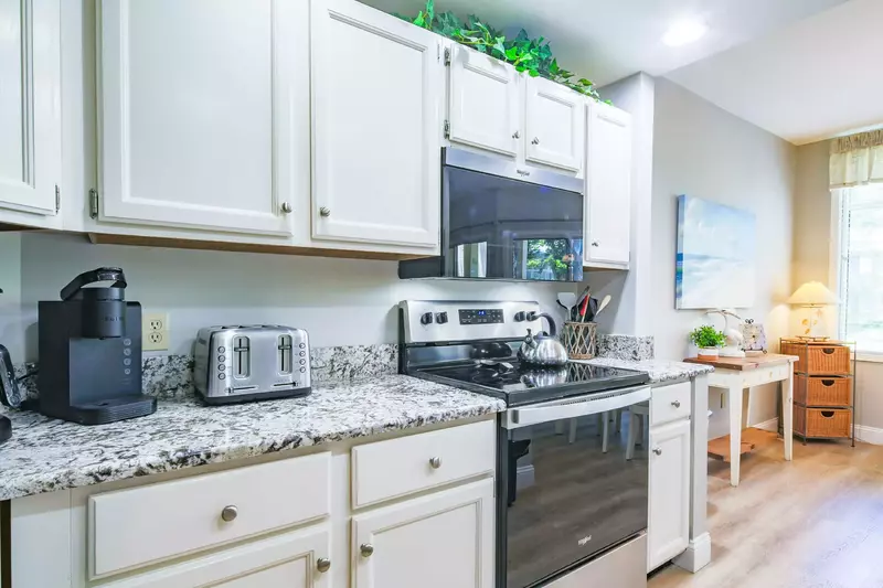 The kitchen features white cabinets, granite counters and stainless/black appliances.