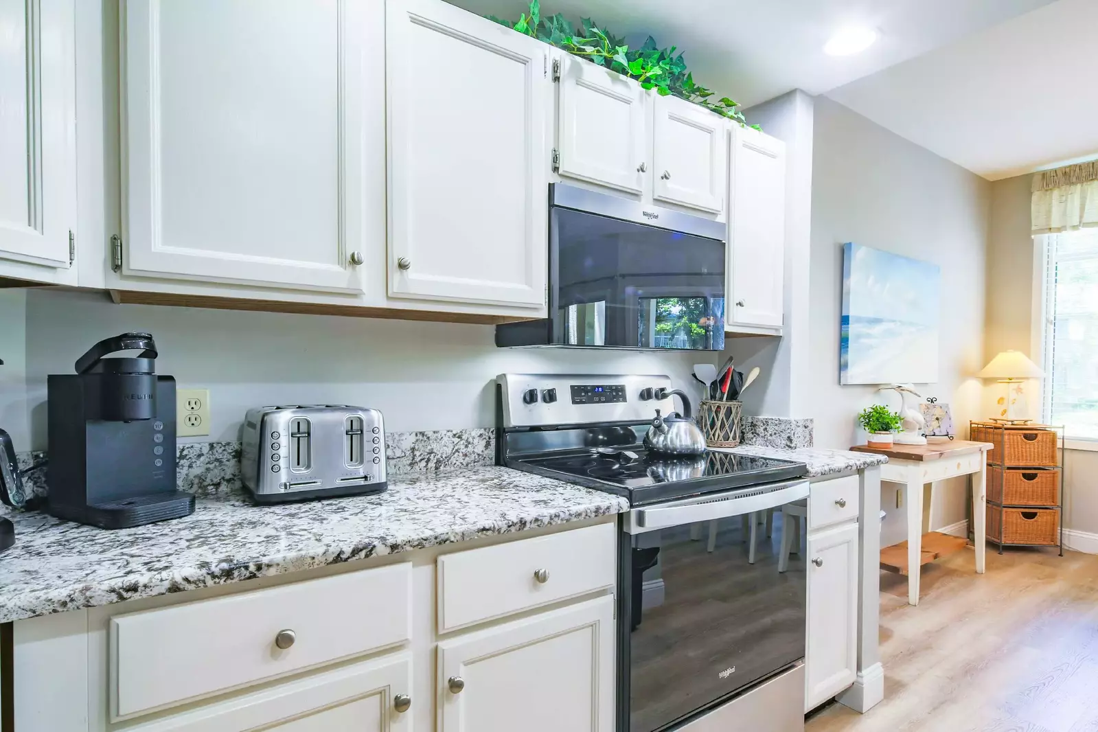 The kitchen features white cabinets, granite counters and stainless/black appliances.