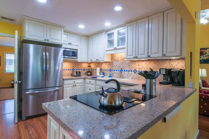 The kitchen features a tiled backsplash, stainless steel appliances and white cabinetry.