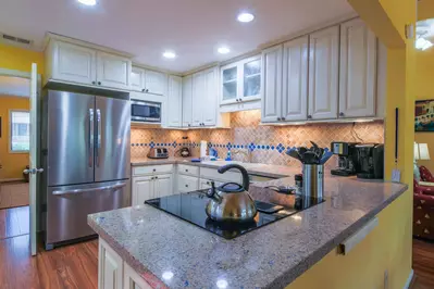 The kitchen features a tiled backsplash, stainless steel appliances and white cabinetry.