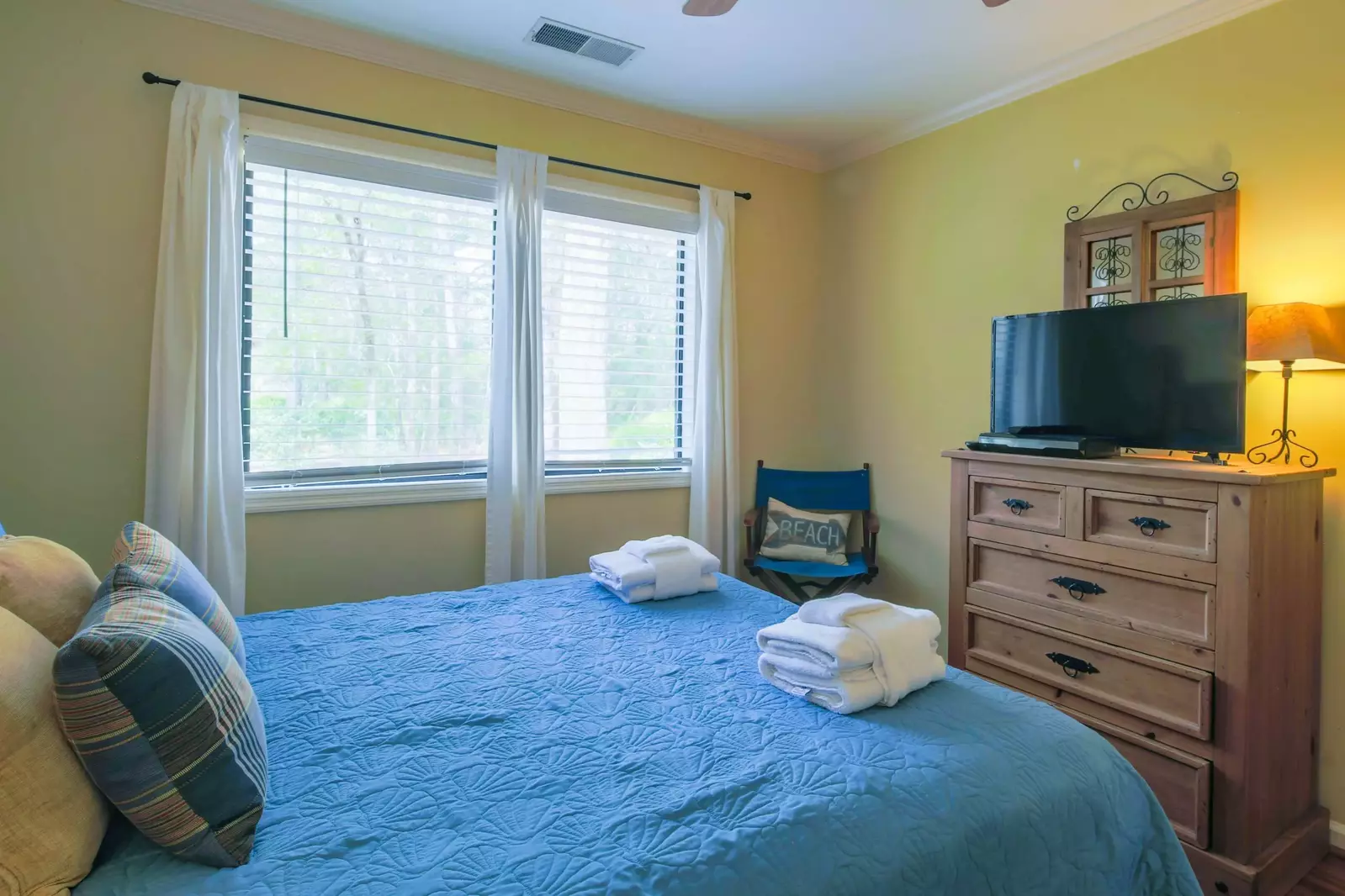 This guest bedroom also has a dresser, ceiling fan and flat screen TV.