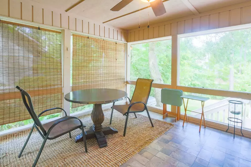 The screened porch has a table & chairs and ceiling fan.