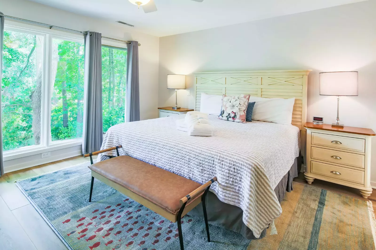 The master suite features a king bed, bench and night stands with reading lamps.