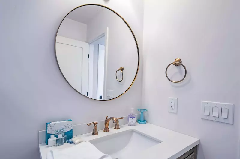 The hallway bathroom features a spacious vanity and round mirror.