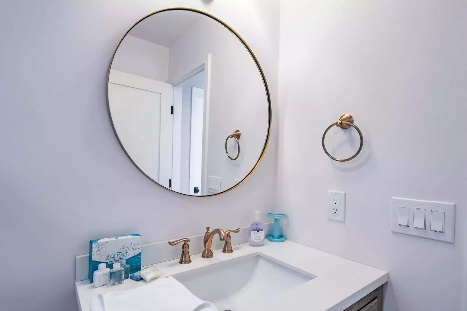 The hallway bathroom features a spacious vanity and round mirror.