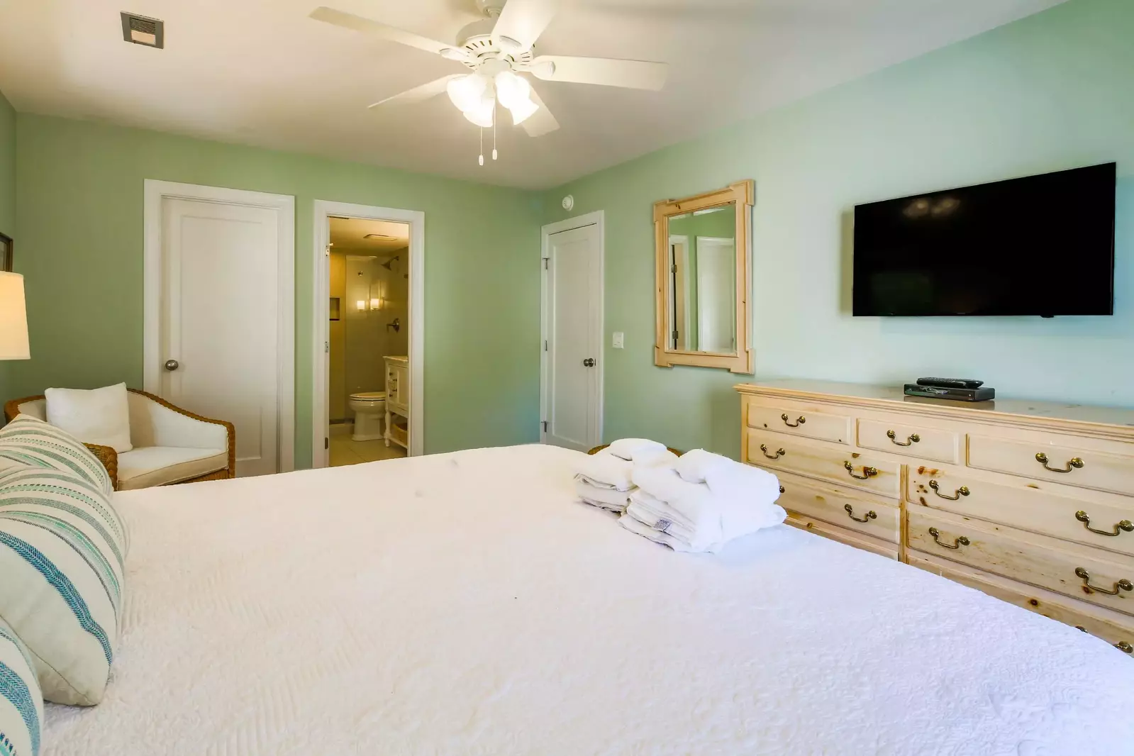 The master suite has a wall mirror, ceiling fan and en suite bathroom.