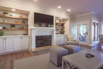 The living room features a wall-mounted TV, built-in bookcases and shiplap accent walls.