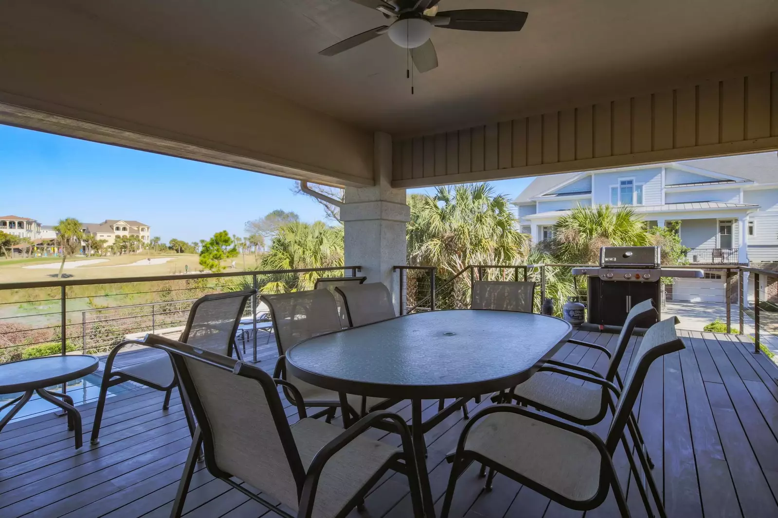 The spacious covered deck features an outdoor dining table, gas grill and steps down to the private pool.