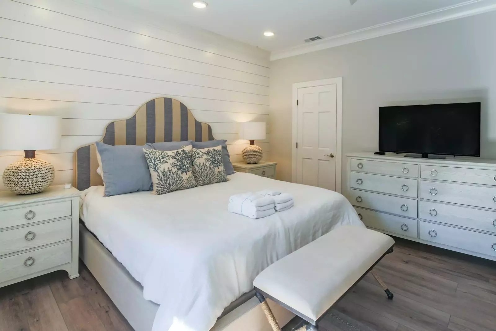 This second master suite features a king bed, night stands with reading lamps and a shiplap accent wall.