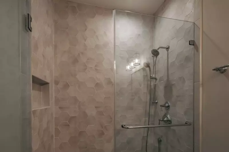 This en suite bathroom also features a honeycomb-tiled, walk-in shower.