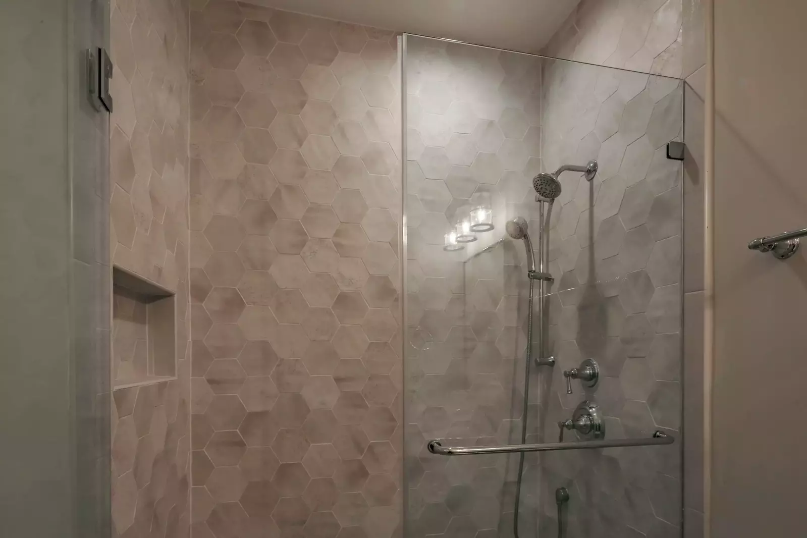 This en suite bathroom also features a honeycomb-tiled, walk-in shower.