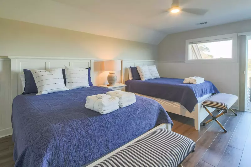 The Queen Suite features two queen beds, a ceiling fan and a night stand with a reading lamp.