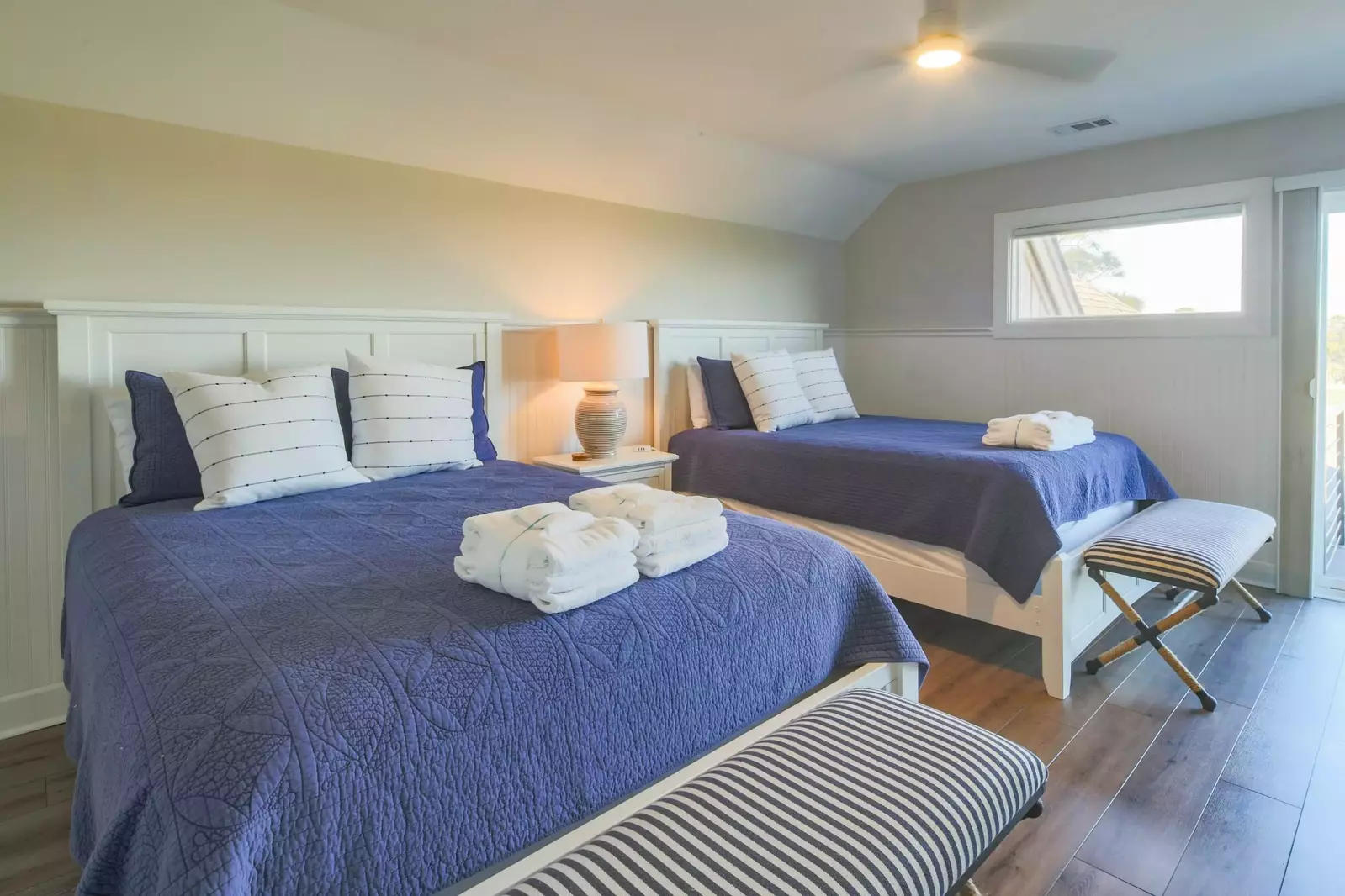 The Queen Suite features two queen beds, a ceiling fan and a night stand with a reading lamp.