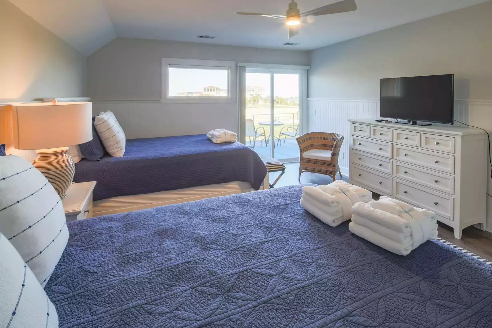 The Queen Suite also features a dresser with TV and sliding door access to the outdoor balcony.