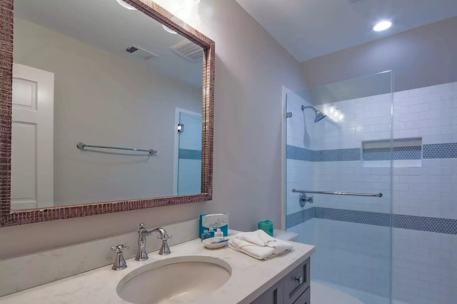 This en suite bathroom for the Queen Suite features a spacious vanity and a tiled, walk-in shower.