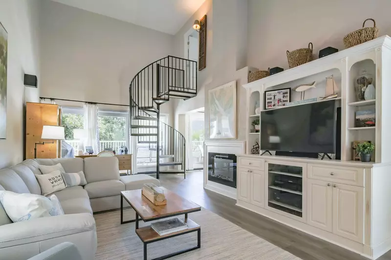 The living room connects to the partially-covered balcony, kitchen and spiral staircase.