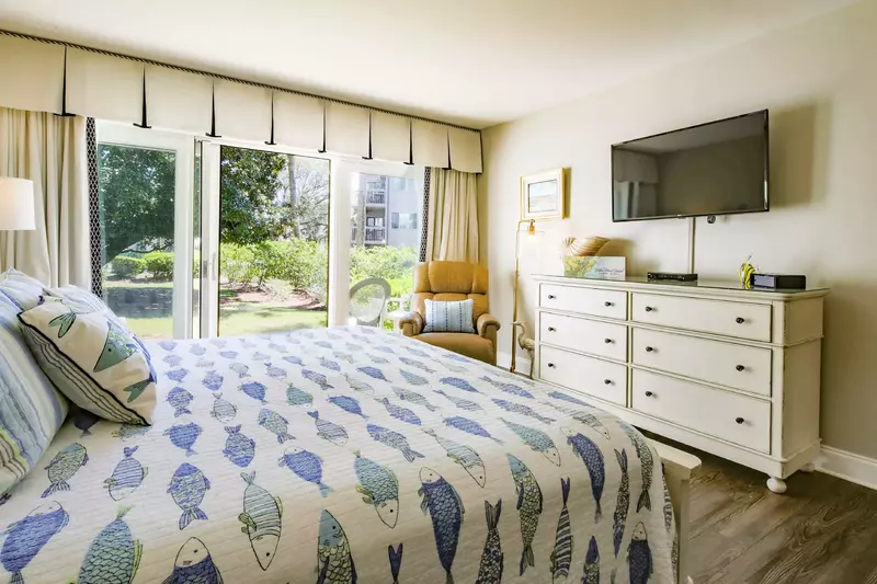 The master suite features lovely natural light, a dresser and wall-mounted TV.