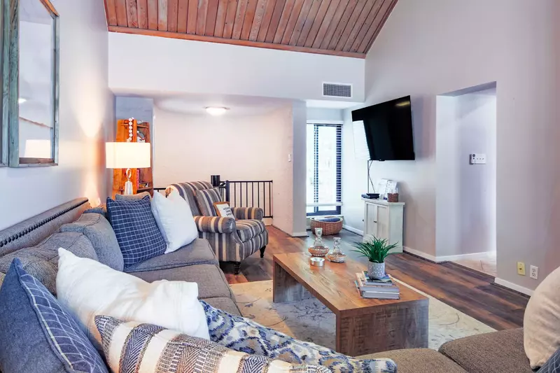 The living room features a spacious sectional, wall-mounted smart TV and vaulted ceilings.