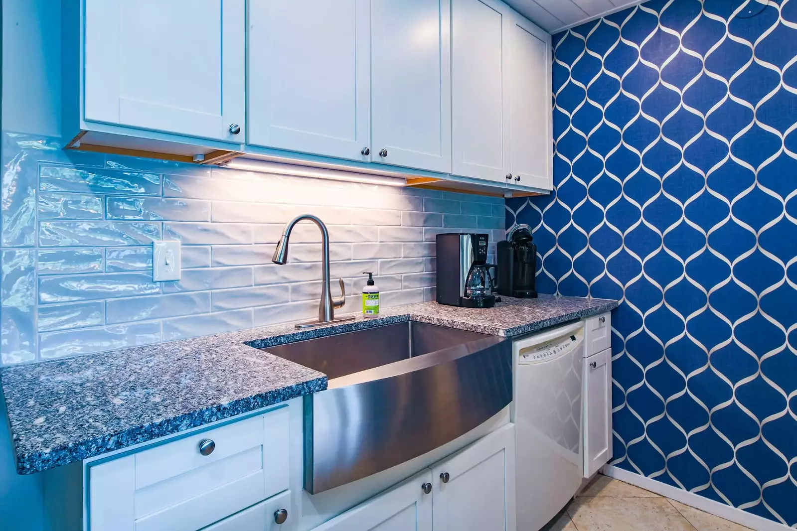 The renovated kitchen features granite countertops, white cabinetry and a tiled backsplash.