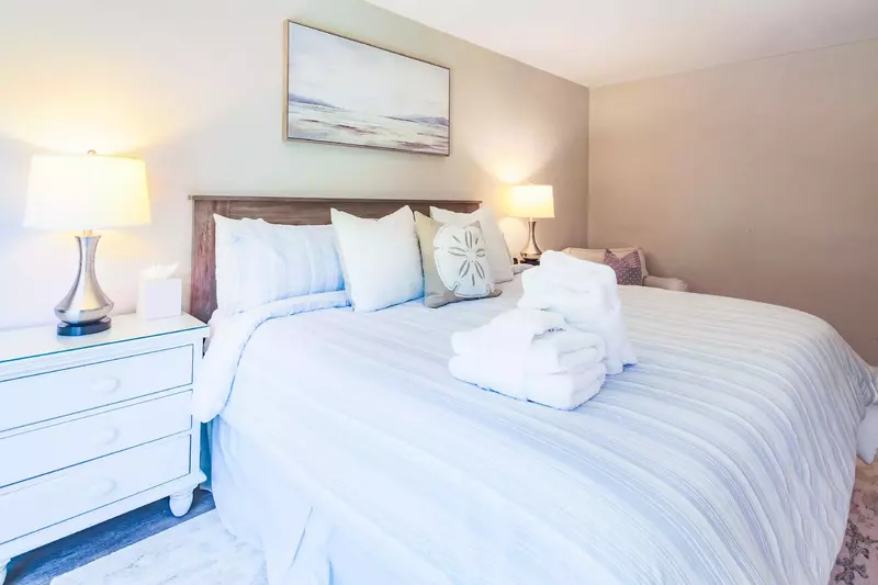 The master suite features a king bed, night stands with reading lamps and an arm chair.